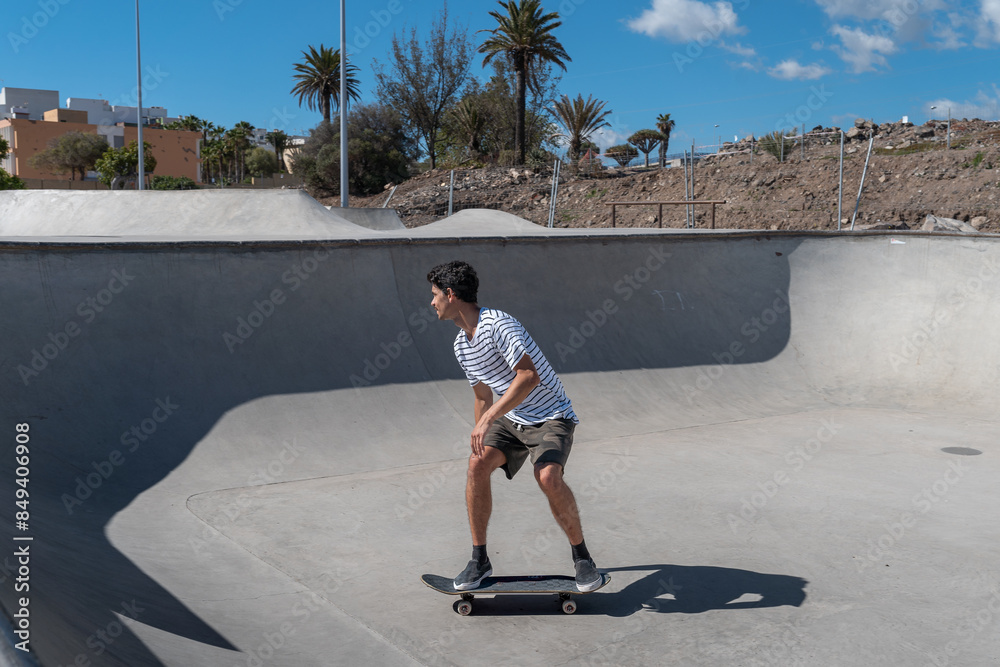 young skater wearing shorts skating in the bowl of a skaterpark in a sunny day young skater wearing shorts skating in the bowl of a skaterpark in a sunny day
