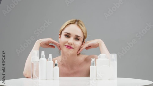 young woman, blonde with fair skin, on a light background next to a variety of natural cosmetic products. Cosmetology advertising concept. Samples of packaging layouts for cosmetic products.