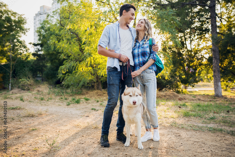funny young stylish couple playing with dog in park funny young stylish couple playing with dog in park