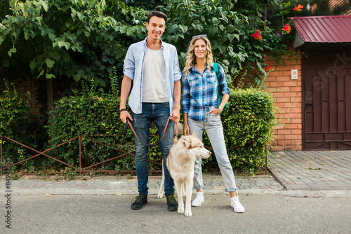 young stylish couple walking with dog in street, man and woman happy together