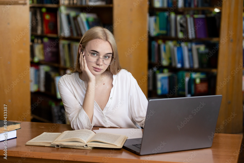 A young teenage girl in the library writes an essay or outline, taking diligent notes. This scene embodies the concepts of passing exams, studying, and education, highlighting her dedication to academ A young teenage girl in the library writes an essay or outline, taking diligent notes. This scene embodies the concepts of passing exams, studying, and education, highlighting her dedication to academ