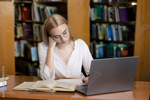A young teenage girl in the library writes an essay or outline, taking diligent notes. This scene embodies the concepts of passing exams, studying, and education, highlighting her dedication to academ