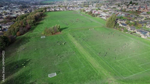 Birds Eye Views of Aerial drone footage of playing fields, football pitch with school children playing during a sports lesson.