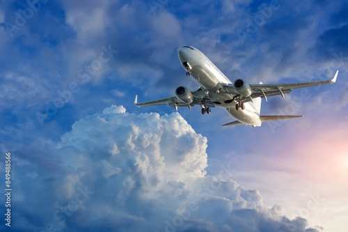 White passenger airplane flying in the sky amazing cumulus clouds. Travel by air transport