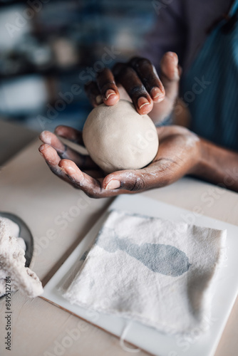 Close up of diverse pottery class attendee's hands doing clay work.