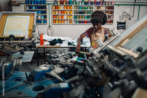 Smiling interracial printing shop worker silkscreen printing at workshop