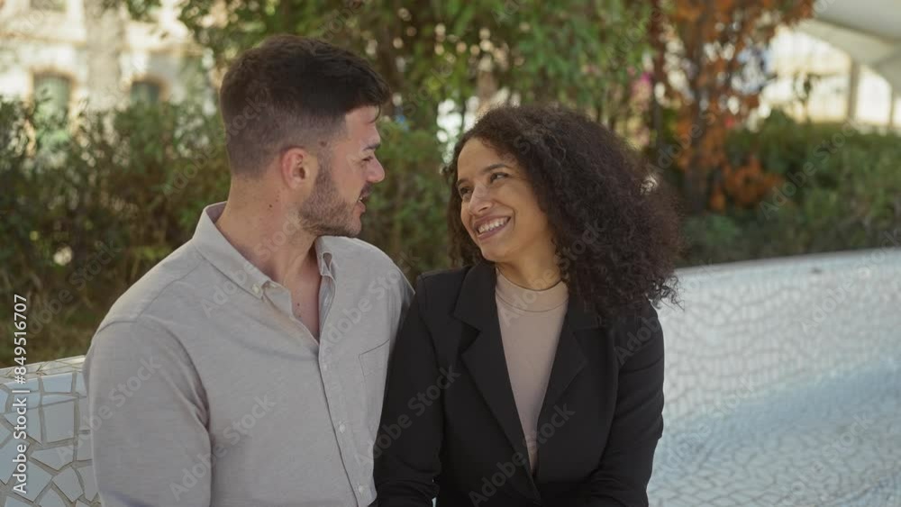 Affectionate interracial couple sitting together on a white bench, surrounded by lush greenery in a public park, sharing a joyful, romantic moment outdoors. Affectionate interracial couple sitting together on a white bench, surrounded by lush greenery in a public park, sharing a joyful, romantic moment outdoors.