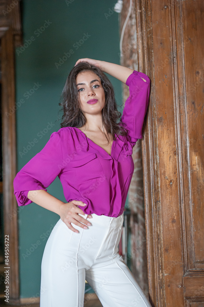 Beautiful young brunette woman in a purple blouse and white pants posing outdoor. Portrait of a beautiful young brunette woman with long hair posing fashion