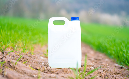 plastic canister with fertilizer pesticide herbicide or fungicide on a green field