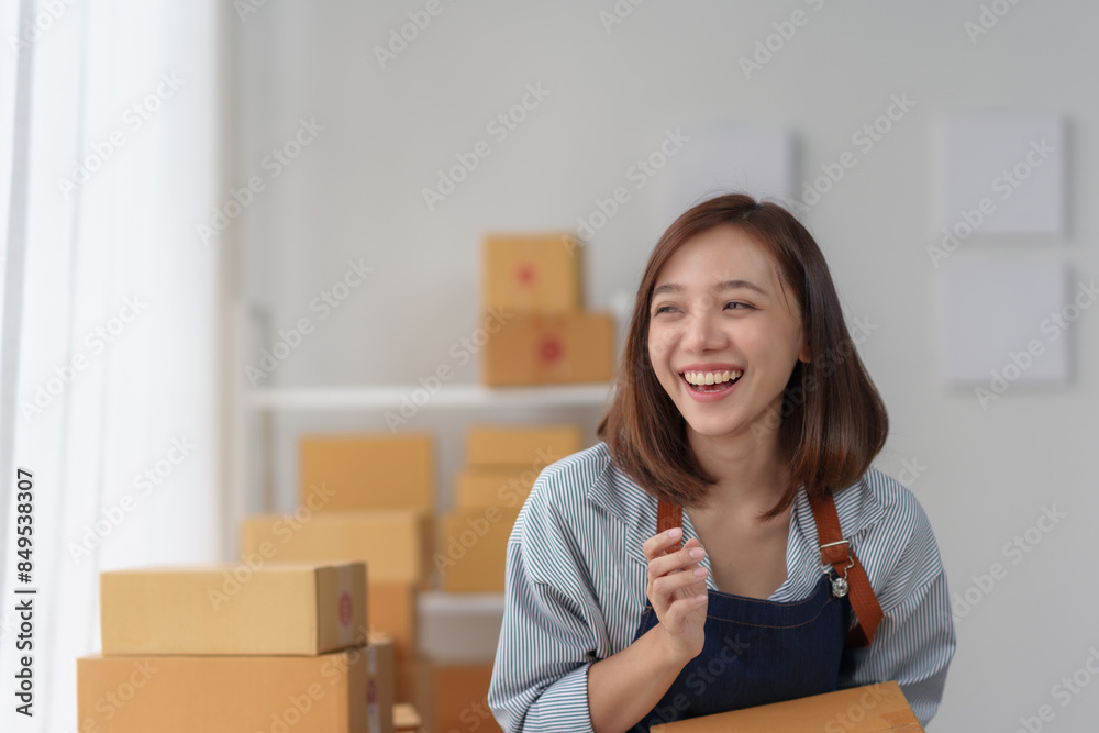 Smiling woman working with boxes and preparing packages in a bright room with shelves in the background. Organizing shipping supplies. Smiling woman working with boxes and preparing packages in a bright room with shelves in the background. Organizing shipping supplies.