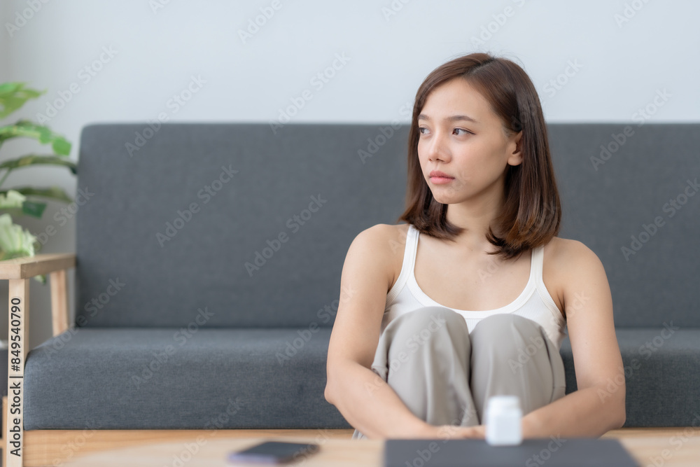 Young woman sitting on sofa at home, looking pensive. Concept of mental health, stress, anxiety, and contemplation. Young woman sitting on sofa at home, looking pensive. Concept of mental health, stress, anxiety, and contemplation.