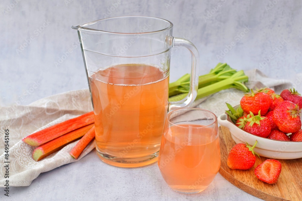 Compote of fresh strawberries and rhubarb with mint leaves in a glass and jug. Compote of fresh strawberries and rhubarb with mint leaves in a glass and jug.