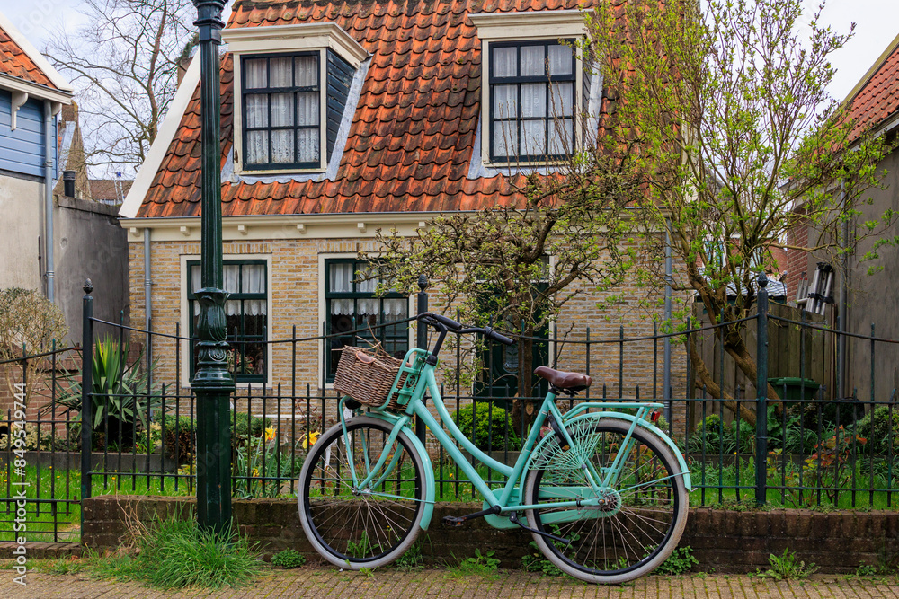 A mint green ladies' bicycle with a cargo basket stands against a wrought-iron garden fence in the Dutch town of Edam A mint green ladies' bicycle with a cargo basket stands against a wrought-iron garden fence in the Dutch town of Edam