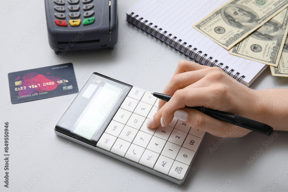 Female hand with calculator and credit card on grey background, closeup. House rent concept Female hand with calculator and credit card on grey background, closeup. House rent concept