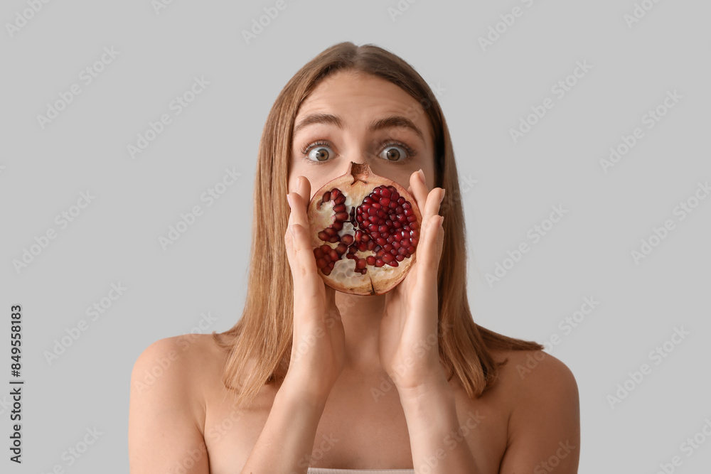 Shocked young woman with pomegranate on light background, closeup Shocked young woman with pomegranate on light background, closeup