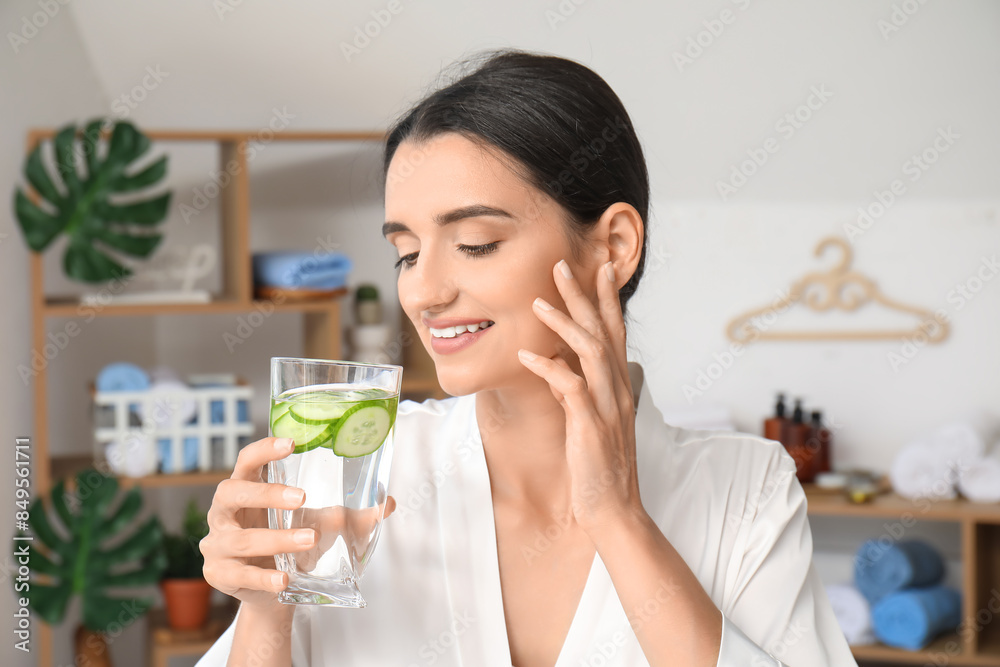 Young woman with glass of cucumber water at home, closeup Young woman with glass of cucumber water at home, closeup