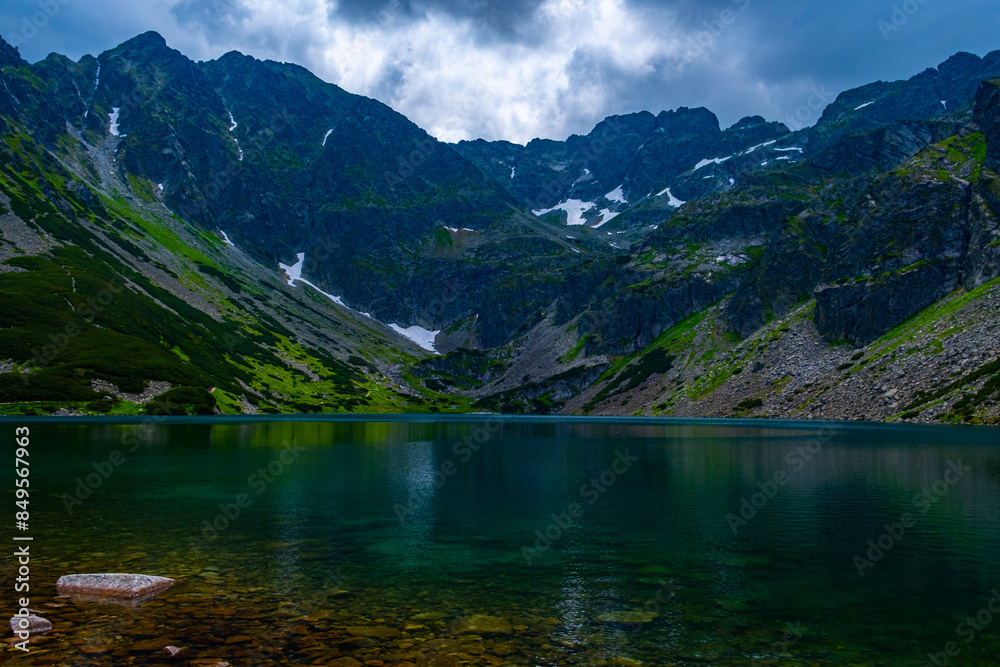 Landscape of rocky mountains and a lake with a rocky bottom in cloudy weather Landscape of rocky mountains and a lake with a rocky bottom in cloudy weather