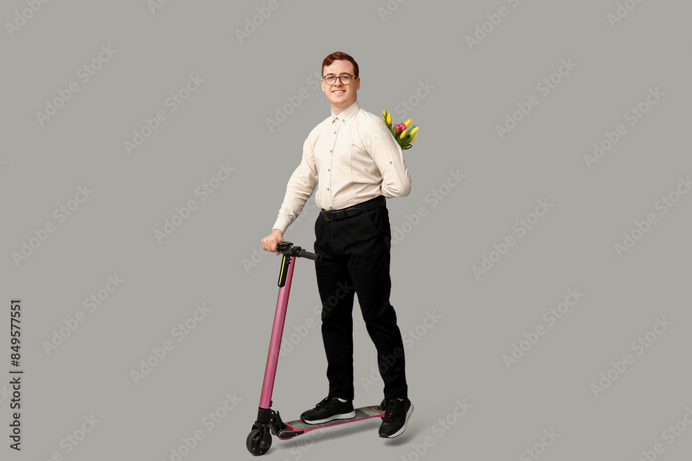 Young man with modern electric kick scooter and bouquet of beautiful tulips on grey background Young man with modern electric kick scooter and bouquet of beautiful tulips on grey background