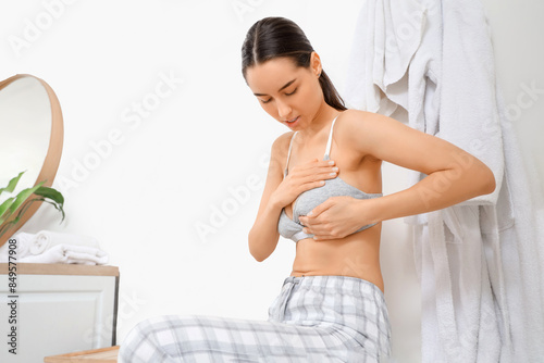 Beautiful young woman checking her breast in bathroom. Cancer awareness concept photo