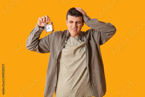 Tired young man with alarm ...