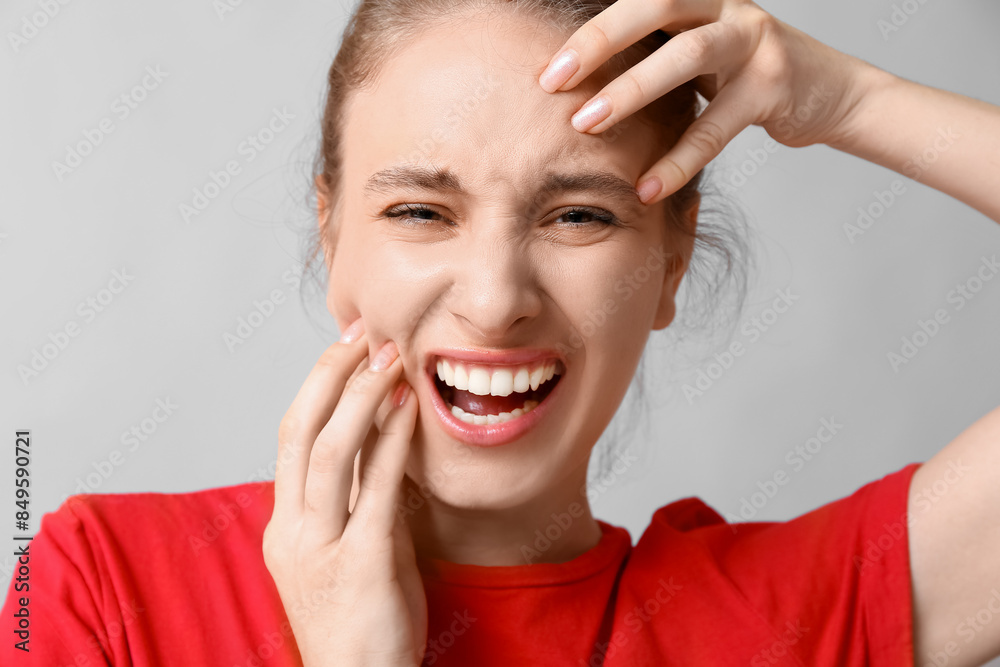 Beautiful young woman suffering from toothache on grey background, closeup Beautiful young woman suffering from toothache on grey background, closeup