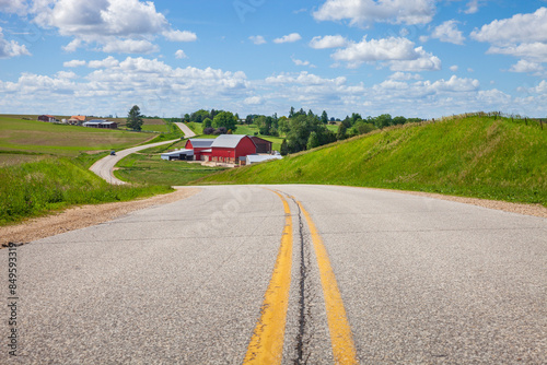 Farm with a red barn on a curving road in the Iowa countryside on a bright spring day