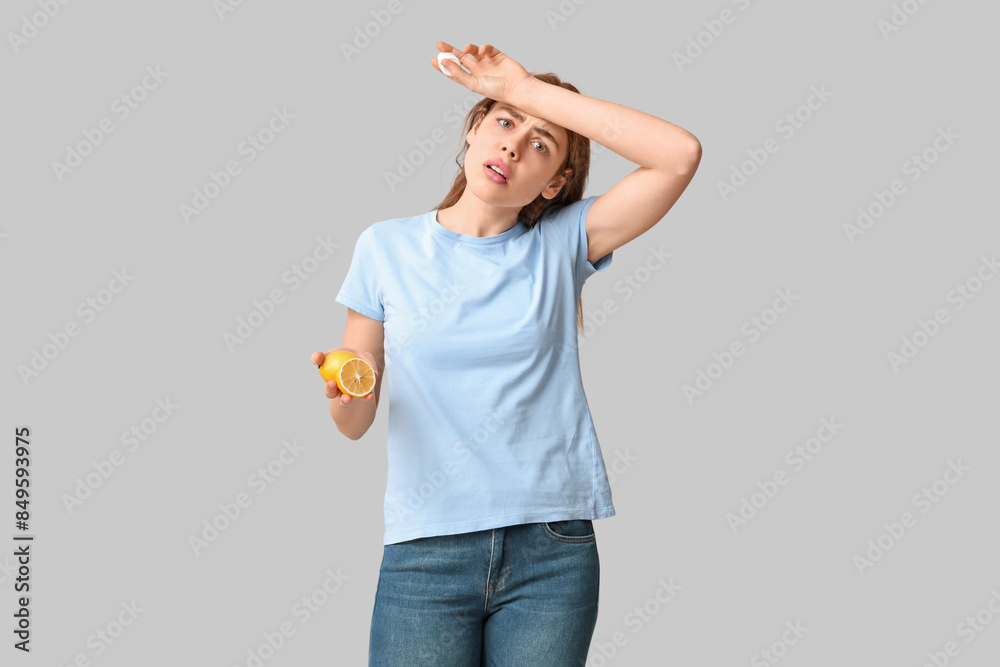 Young woman with lemon and nasal spray suffering from allergy on grey background Young woman with lemon and nasal spray suffering from allergy on grey background