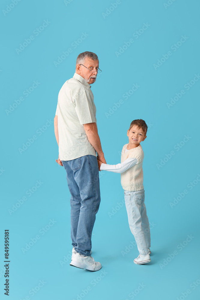 Grandfather with his happy cute little grandson on blue background Grandfather with his happy cute little grandson on blue background