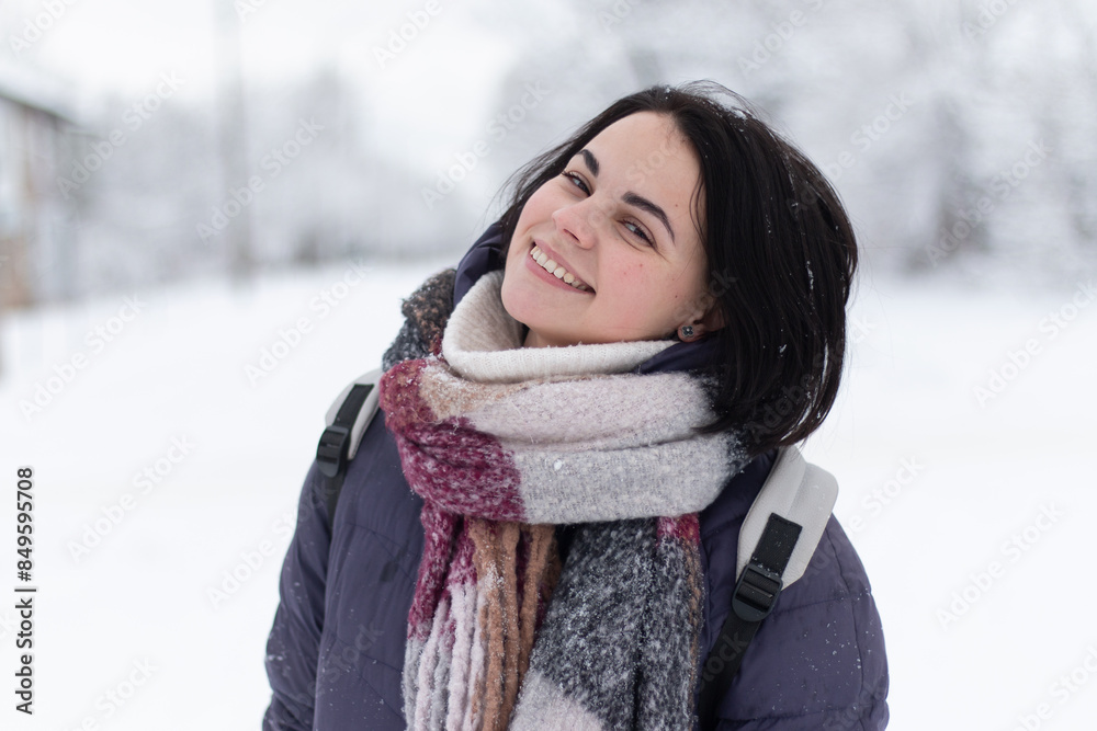 Young smiling beautiful woman wearing scarf outdoors during snowfall Young smiling beautiful woman wearing scarf outdoors during snowfall