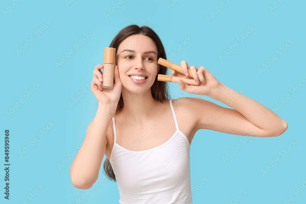 Beautiful young woman holding set of decorative cosmetics on blue background Beautiful young woman holding set of decorative cosmetics on blue background