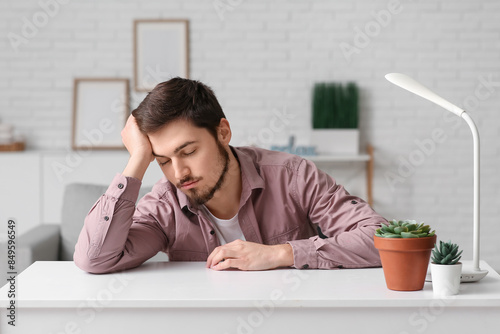 Tired young man at table in...