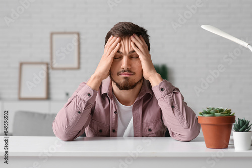 Tired young man at table in...