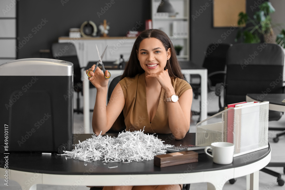 Young secretary with scissors, shredded paper and shredder in office Young secretary with scissors, shredded paper and shredder in office