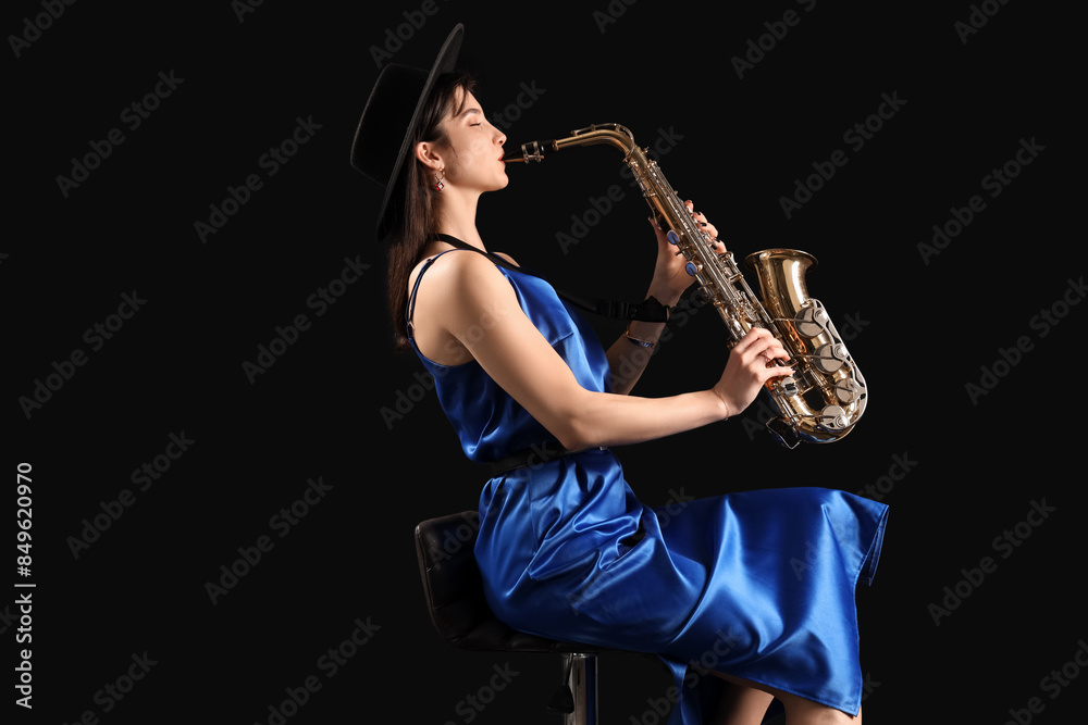 Naklejka premium Beautiful woman playing saxophone on dark background