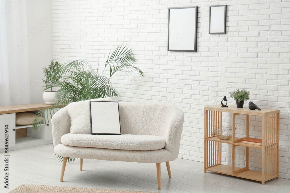 Fototapeta premium Modern living room with houseplant and blank picture frame on sofa and white brick wall