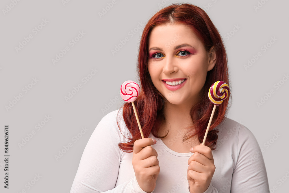 Beautiful young woman with tasty lollipops on grey background Beautiful young woman with tasty lollipops on grey background