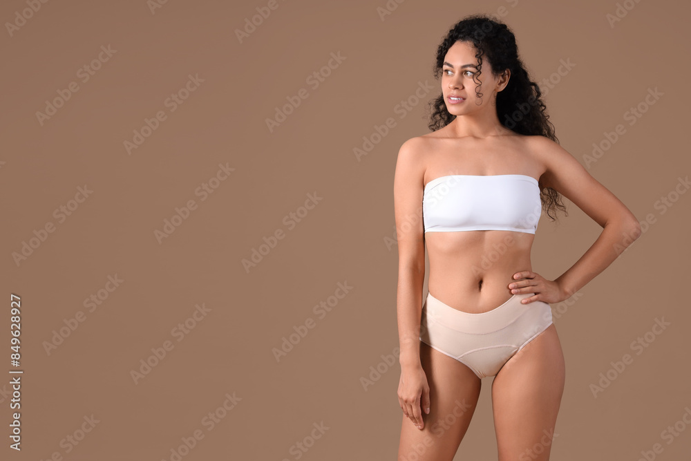 Young African-American woman in menstrual panties on brown background Young African-American woman in menstrual panties on brown background