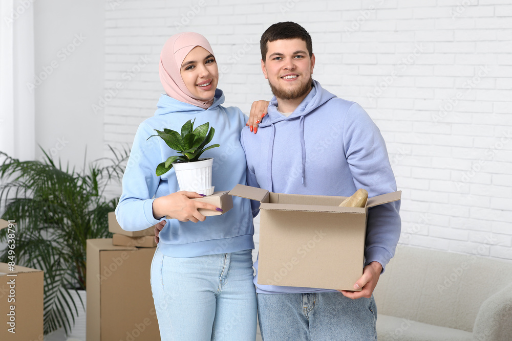 Young happy Muslim couple with belongings in their new house