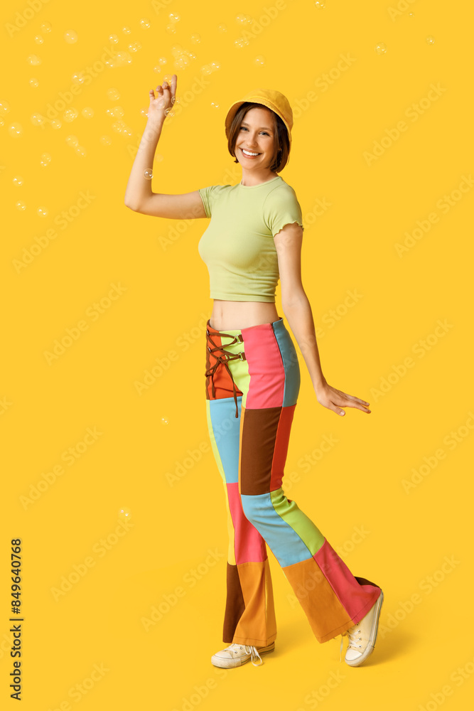 Happy teenage girl blowing soap bubbles on yellow background Happy teenage girl blowing soap bubbles on yellow background