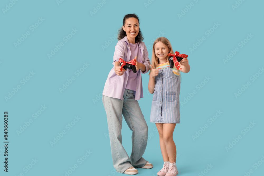 Mature woman and her little granddaughter with gift game pads on blue background Mature woman and her little granddaughter with gift game pads on blue background