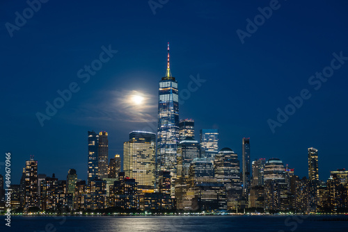 Manhattan skyline viewed from Hoboken, New Jersey, at dusk, with the moon behind some clouds.