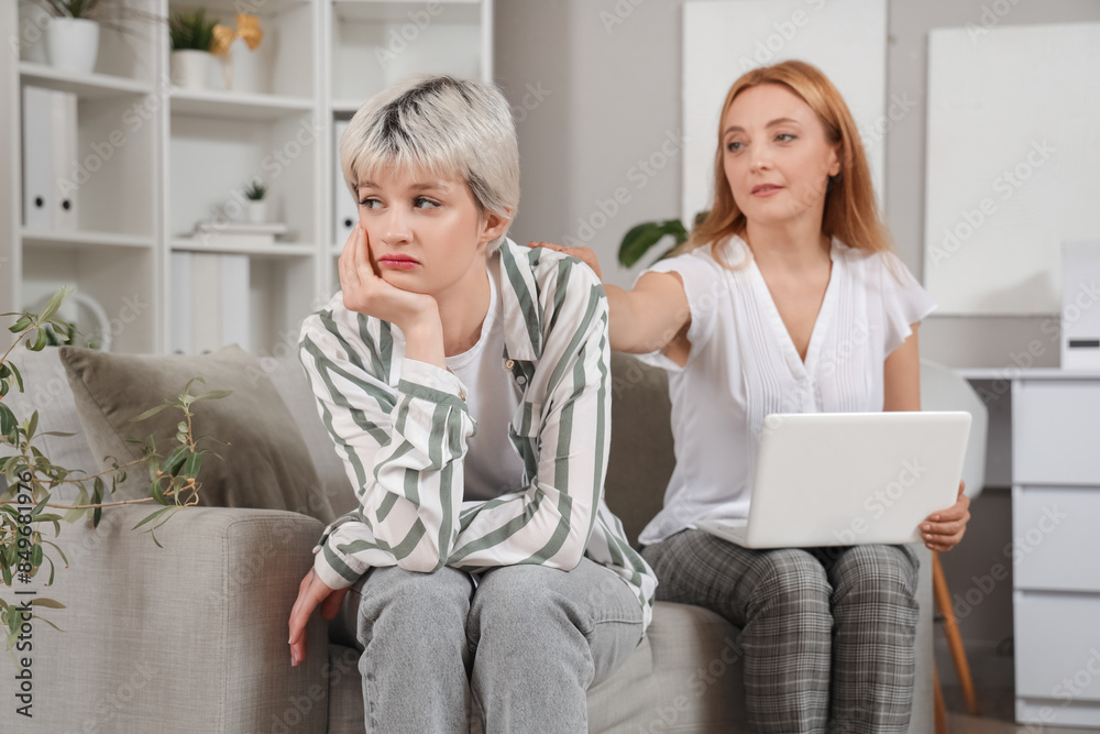 Sad teenage girl with psychologist sitting on sofa in office Sad teenage girl with psychologist sitting on sofa in office