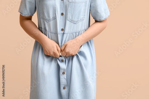 Young woman suffering from cystitis on beige background, closeup