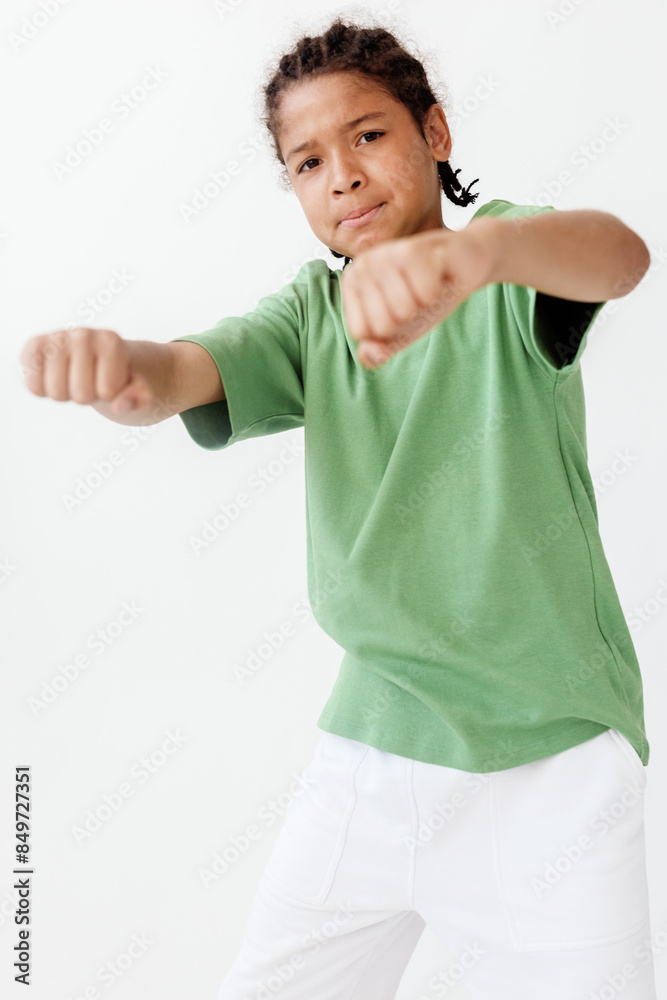 Confident young boy in green shirt and white pants raises fist in trendy gesture Confident young boy in green shirt and white pants raises fist in trendy gesture