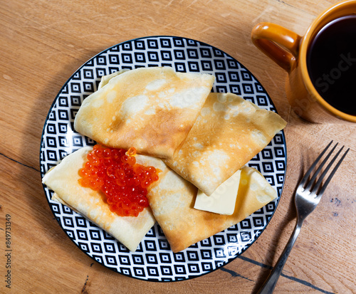 Photography Service plate containing fried hotcakes with piece of butter and red caviar and necessary table laying