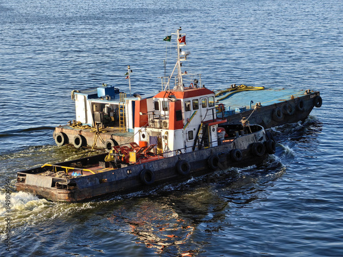 A small tugboat pushes a barge through the water