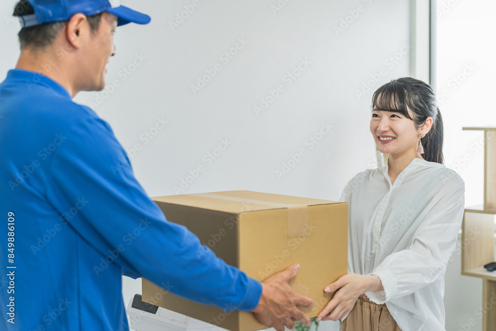 Fototapeta premium 宅配・配送の荷物の集荷をお願いする女性客と配送員・配達員の男性 