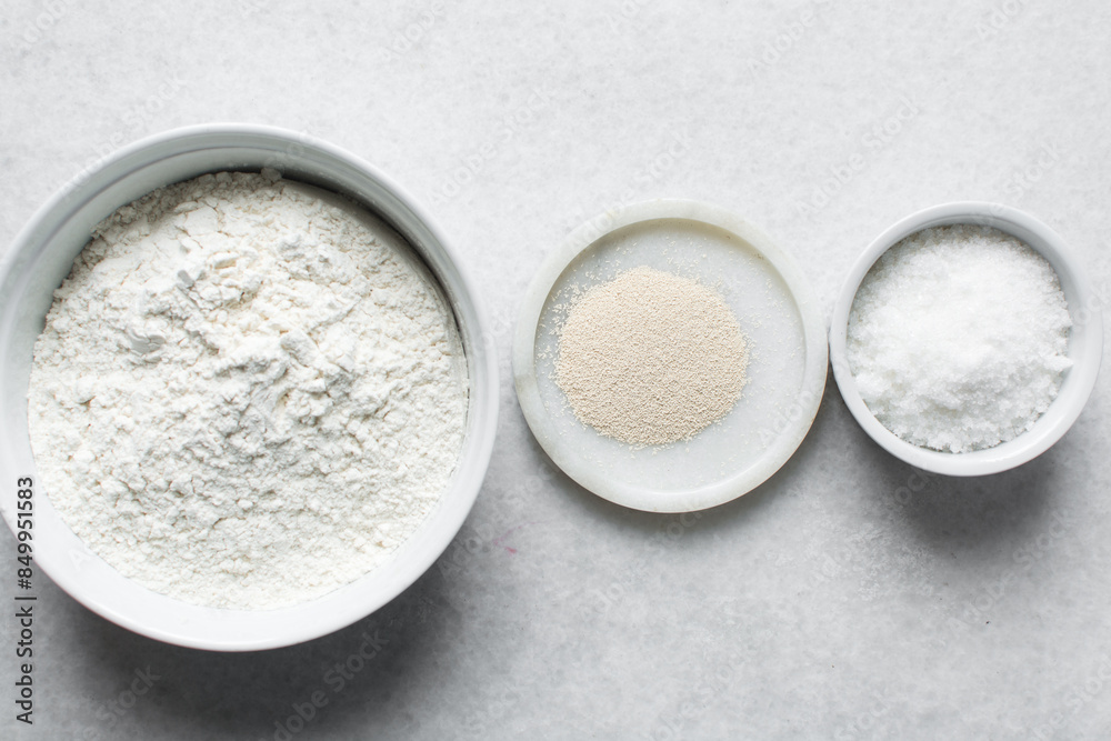 Overhead view of mise en place of ingredients for making nigerian puff-puff, flatlay of flour yeast sugar for puff-puff on a marble countertop, process of making puff-puff or bofrot Overhead view of mise en place of ingredients for making nigerian puff-puff, flatlay of flour yeast sugar for puff-puff on a marble countertop, process of making puff-puff or bofrot