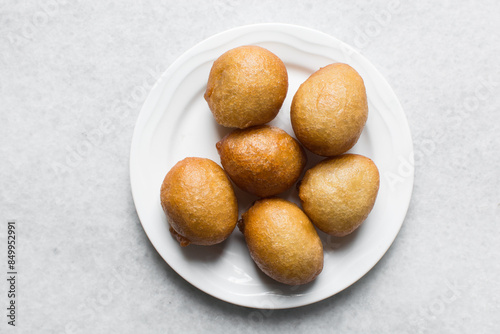 Overhead view of nigerian puff-puff on a white plate, nigerian fried dough balls, flatlay of homemade bofrot on white dish