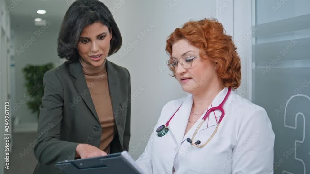 Healthcare specialist showing clipboard to woman patient in medical hall closeup Healthcare specialist showing clipboard to woman patient in medical hall closeup